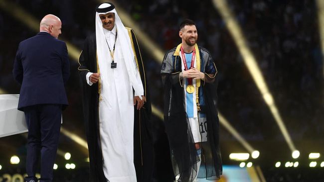 Lionel Messi mengangkat trofi Piala Dunia 2022 sambil memakai bisht, pakaian tradisional bangsa Arab setelah diberi Emir Qatar Sheikh Tamim bin Hamad Al Thani.